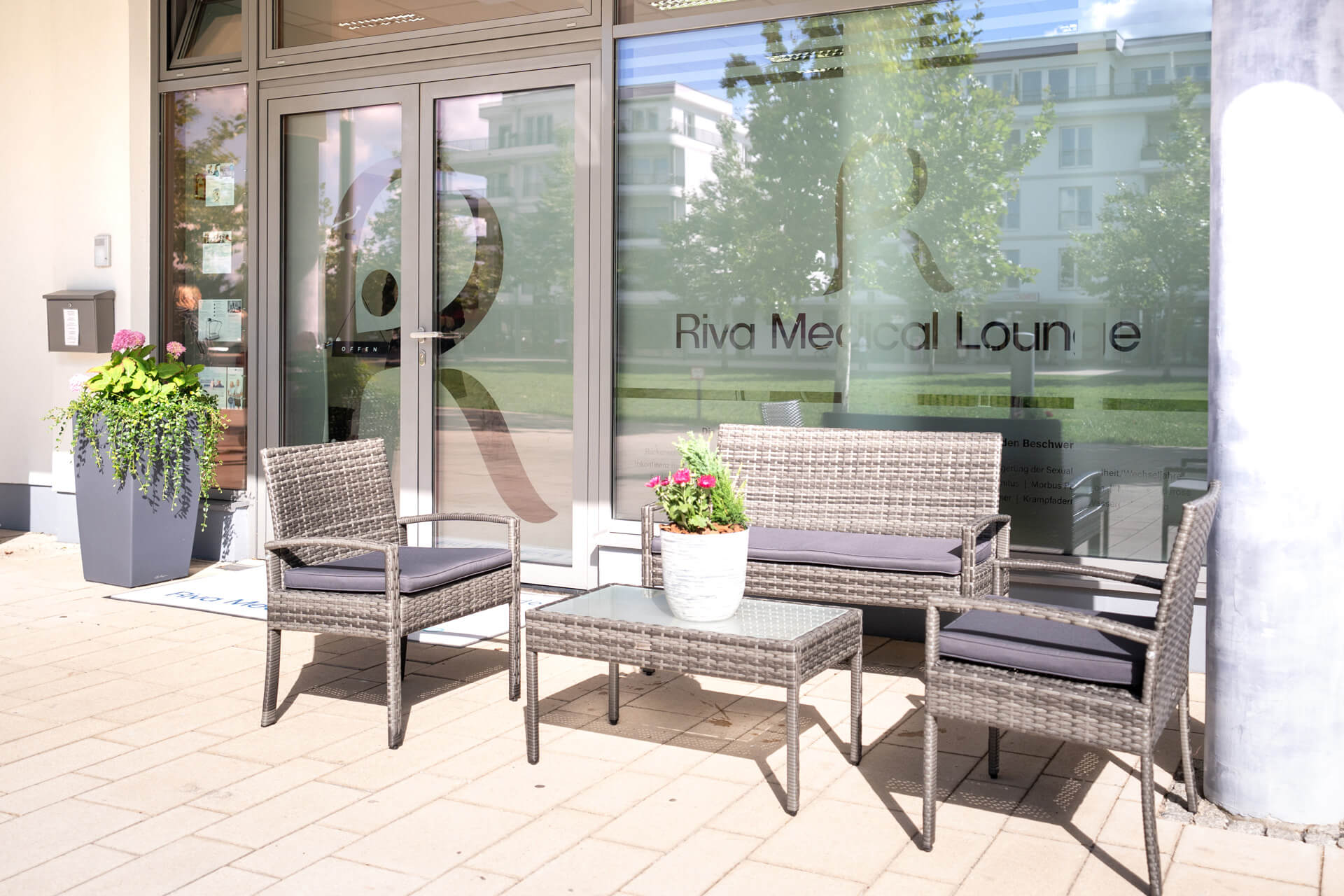 Riva Medical Lounge: Wartebereich mit Gartenmöbeln vor dem Eingang. Entspannende Atmosphäre.
